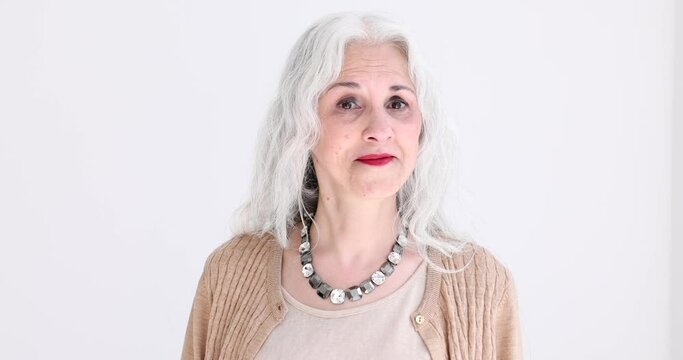 Doubting elderly woman with grey hair asking in studio