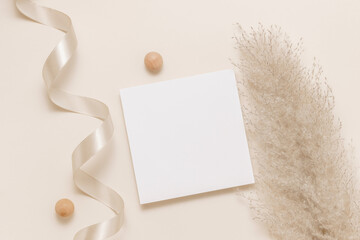 Minimal mockup paper sheet card for branding, invitation and greeting. Aesthetic paper card with pampas grass and ribbon top view, flat lay