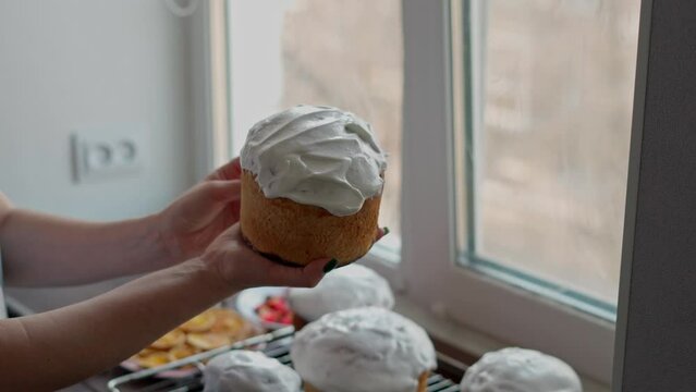 Caucasian Woman's Hand Spreads white Glaze on freshly cooked Easter Cakes. Cooking homemade traditional Easter Cakes