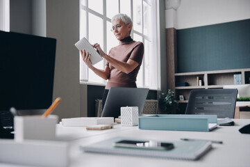 Confident senior businesswoman using digital tablet while working in the office