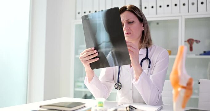 Focused medic in uniform examines x-ray picture of joint