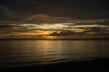 Picturesque sunset on the beach of Siquijor in the Philippines, the whole sky glows in golden yellow color.
