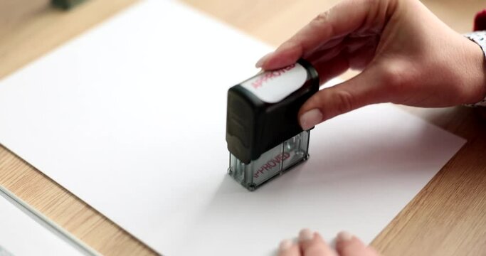 Woman leaves stamp Approved on blank paper sheet in office