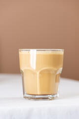 Fresh hot coffee cappuccino in a glass on table, minimalism.
