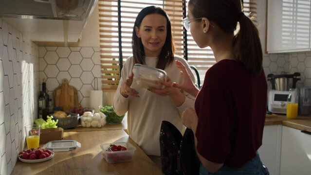 Caucasian mother giving a lunch box to daughter to school. Shot with RED helium camera in 8K. 