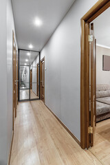 long corridor in interior of entrance hall of modern apartments with doors, cabinets, shelves and a mirror