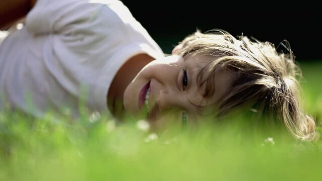 Joyful child happy expression laid on grass in beautiful sunny day. One young boy laughing and smiling. Kid being tickled