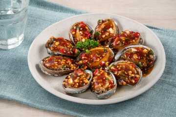 Delicious steamed abalone with Taiwanese five flavor sauce on wooden table background.