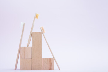 Composition of bamboo toothbrushes and wooden podium blocks. The concept of an eco-friendly lifestyle and the reduction of plastic waste. Minimalism