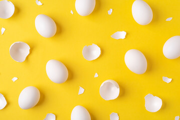 Minimalistic Easter background. White Easter eggs and shells on a bright yellow background. Top view.