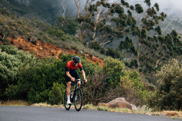 Obraz premium Young male cyclist practicing in wild terrain. Professional triathlete riding road bike.