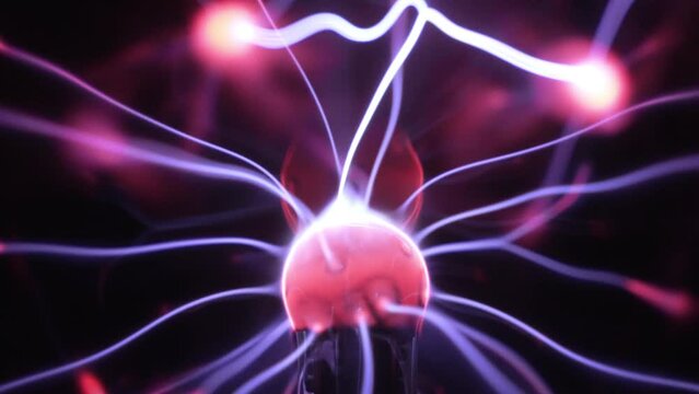 Plasma globe in slow motion. Blue and purple light beams, energy rays split in two points inside the ball. Tesla coil electric discharge. Close up.