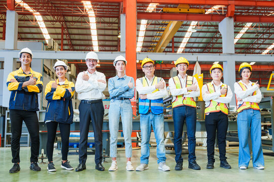Portrait of smiling group of diverse corporate colleagues standing with folded arms wearing in row together at the modern metalwork warehouse factory. Metal Sheet Roofing forming machine