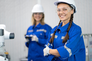 Portrait of smiling female robotics engineer wearing white safety helmet happy work in technology facility. Young beautiful woman worker confidentiality working in the futuristic business. copy space.