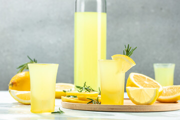 Italian traditional liqueur limoncello with rosemary and lemons on a light background. place for...