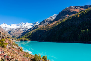 Naklejka na ściany i meble Autumnal landscape of the Lake Place Moulin, an artificial glacial lake with turquoise water in the italian Alps, on the border with Switzerland