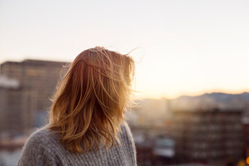 Young blonde woman in city at sunset