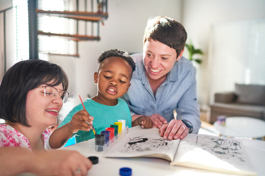 Happy lesbian couple painting with son at home