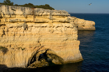 Landscape of Albandeira beach, cliffs, and natural arch in the Algave region at sunset. Portugal.