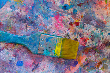 Paintbrush lying on table with paint splatter in an artists studio.