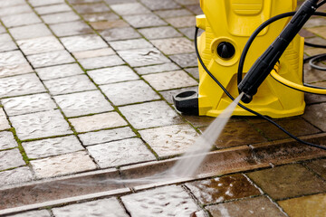Cleaning dirty block Pavement Paving Stones and Concrete Gutter with Water jet from High Pressure Washer. Copy space. High Pressure Cleaning Service.