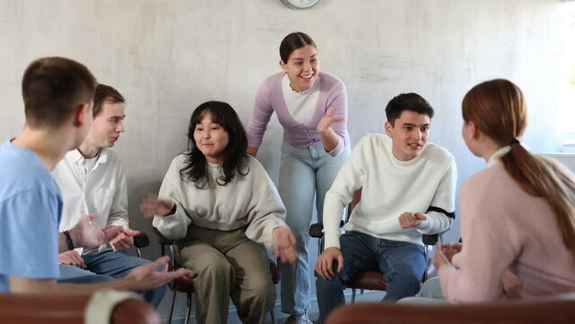 Group of cheerful carefree young students relaxing and chatting amicably during recess between lectures in auditorium. High quality 4k footage