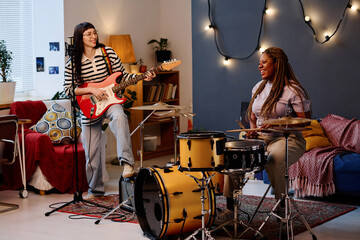 Young women playing guitar and drums together in studio during repetition
