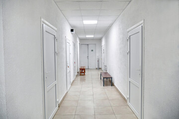 Corridor with white walls, white plastic doors and communications.