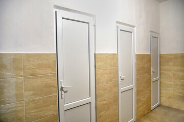 Corridor with tiled walls, white plastic doors and communications.