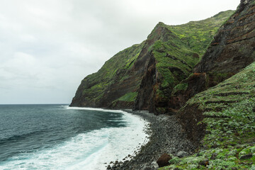 Volcanic beach and cliffs in Madeira Island. Atlantic ocean waves and rocky beach