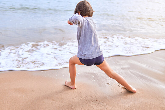 boy practicing martial arts on the beach. unrecognizable elementary age boy making karate katas