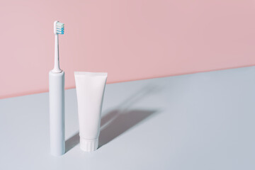 Electric toothbrush with toothpaste against a blue-pink background.