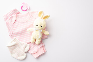 Baby shower concept. Top view photo of infant clothes pink shirt pants socks soother and knitted bunny toy on isolated white background with copyspace