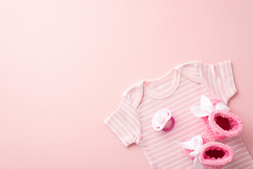 Baby clothing concept. Top view photo of pink shirt knitted booties and pacifier on isolated pastel pink background with copyspace