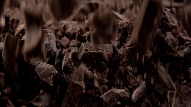 crushed chocolate in motion. pieces of chocolate fall. chocolate chips close-up. cooking brown sweets. cocoa product in the process of preparation.