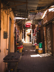 Rays of light in the dusty streets and alleys of the Medina of Marrakech, Morocco, dark city with sunlight and parked bikes and wares