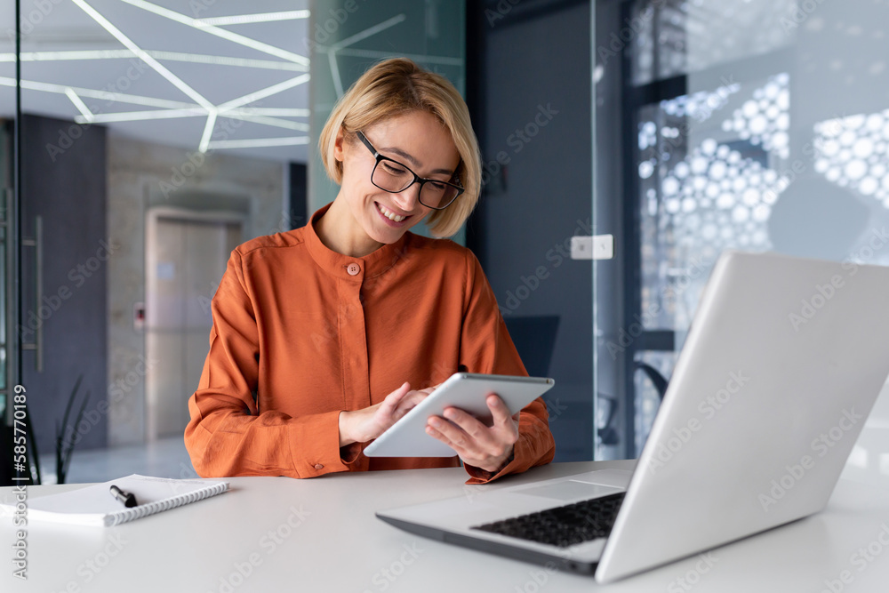 Wall mural young successful businesswoman at workplace is satisfied with results of achievement at work smiling