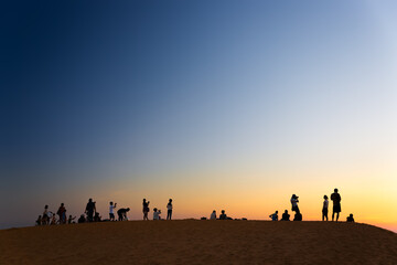 Fototapeta na wymiar MUI NE, VIETNAM - FEBRUARY 08, 2014: Tourist watching sunset on red sand dunes close to South China Sea