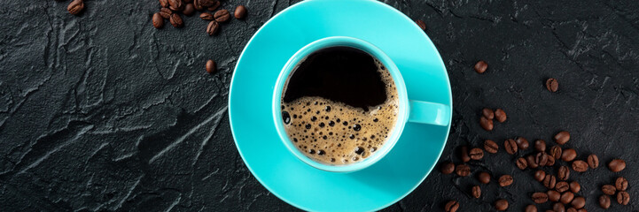 Blue coffee cup and coffee beans panorama, overhead flat lay shot on a black stone background with...