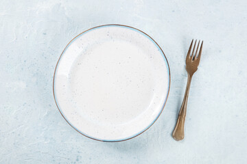 An empty white plate with a blue rim, with a fork, overhead flat lay shot, the concept of food