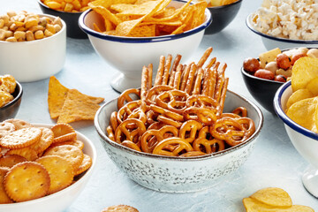 Fototapeta na wymiar Salty snacks, party mix. An assortment of crispy appetizers in bowls on a table. Crackers, sticks etc