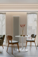 Interior design of dining room interior with round table, gray chair, green shelf, vase with flowers, big windows, radiator, rug, round pillow, curtain and personal accessories. Home decor. Template.