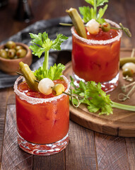 Bloody mary cocktail with garnishes on rustic wooden table