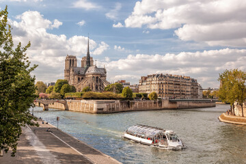 Notre Dame cathedral with tourist boat on Seine during spring time in Paris, France