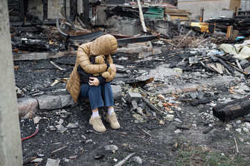 A girl next to a house destroyed by the war. War in Ukraine. Ukrainian refugees. Child in the ruins...