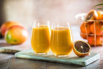 Two mango lassi or kesar milk in glasses. Indian healthy ayurvedic cold drink with mango. Freshness lassi made of yogurt, water, spices, fruits and ice.