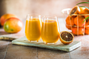 Two mango lassi or kesar milk in glasses. Indian healthy ayurvedic cold drink with mango. Freshness lassi made of yogurt, water, spices, fruits and ice.