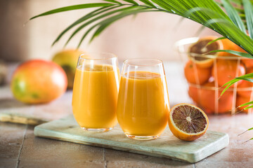 Two mango lassi or kesar milk in glasses. Indian healthy ayurvedic cold drink with mango. Freshness lassi made of yogurt, water, spices, fruits and ice.