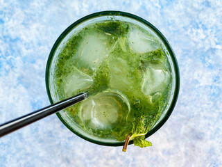 A glass of mojito with a drinking straw top view on a light blue background
