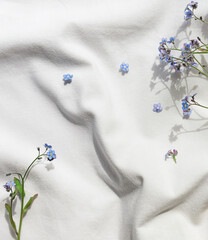 White organic cotton blanket with forget-me-not flowers. Copy space